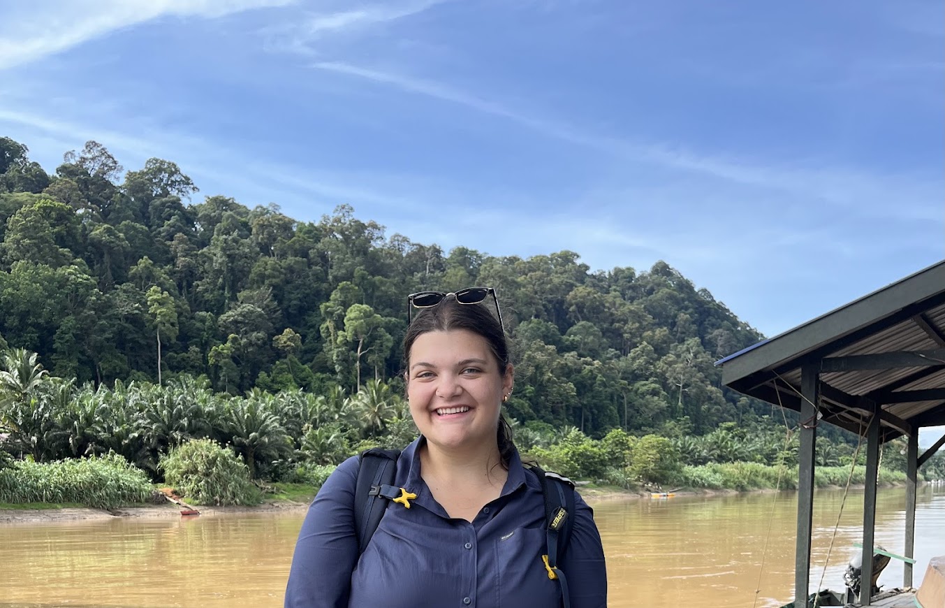 Lindsey Mitchell standing and smiling in front of a river and rainforest in Borneo